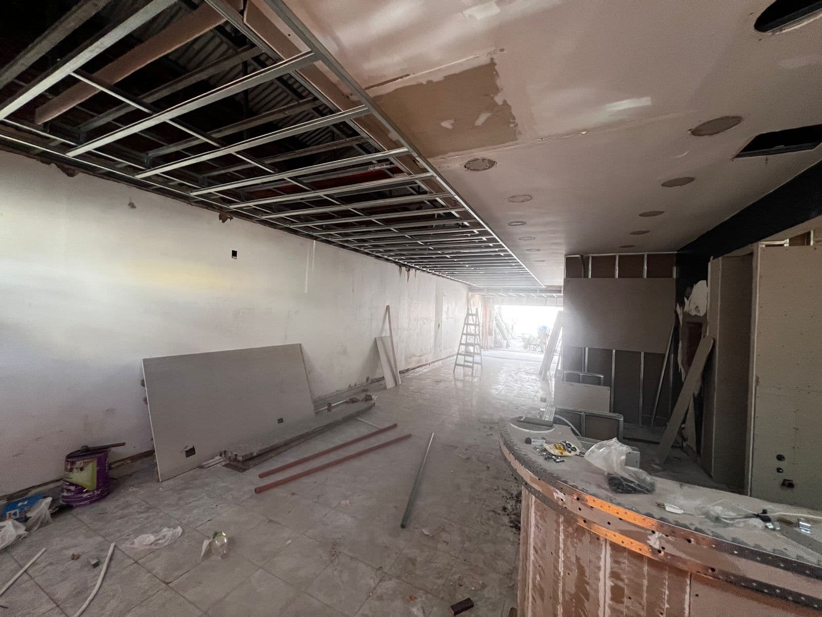 Salón comercial en obra con cielorraso e instalaciones visibles
